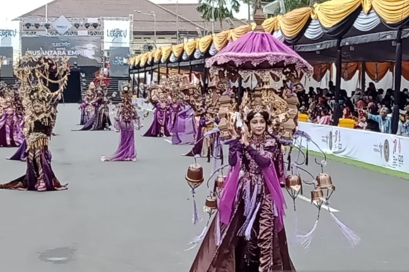 Peserta Defile Majapahit dengan busana dominan warna ungu dengan aksesoris kuning keemasan berlenggak-lenggok di Jalan Sudarman Jember, Minggu (7/8/2022). (ANTARA/Zumrotun Solichah)